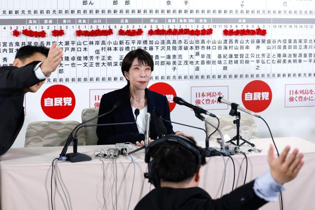 TV staff members gesture in the direction of the camera as Japan's Prime Minister and President of the Liberal Democratic Party (LDP), Sanae Takaichi (C), speaks with media on the House of Representatives election day at the LDP headquarters in Tokyo on February 8, 2026. (Photo by Kim Kyung-Hoon / POOL / AFP)