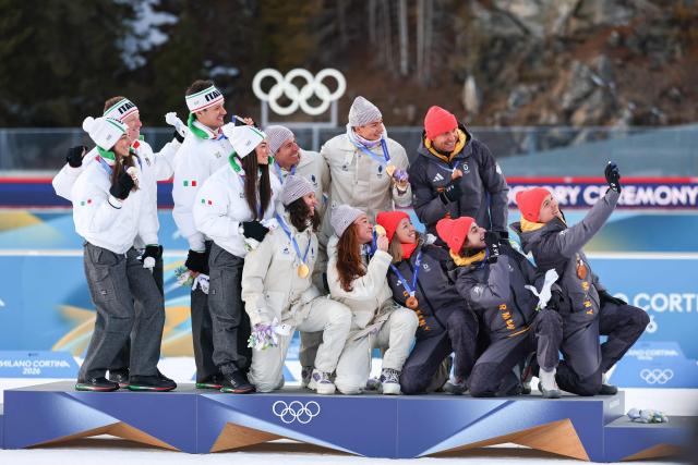 Silver medallists Italy's Tommaso Giacomel, Italy's Lukas Hofer, Italy's Dorothea Wierer and Italy's Lisa Vittozzi, gold medallists France's Eric Perrot, France's Quentin Fillon Maillet, France's Lou Jeanmonnot, France's Julia Simon and bronze medallists Germany's Justus Strelow, Germany's Philipp Nawrath, Germany's Vanessa Voigt, Germany's Franziska Preuss, pose for a selfie on the podium of the mixed biathlon 4 x 6km relay event during the Milano Cortina 2026 Winter Olympic Games at the Anterselva Biathlon Arena (Sudtirol Arena) in Anterselva (Val Pusteria) on February 8, 2026. (Photo by FRANCK FIFE / AFP)