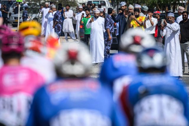 People watch the pack rides during the 2nd stage of the Tour of Oman cycling race from Al Rustaq Fort to Yitti Hills, on February 8, 2026. (Photo by Loic VENANCE / AFP)