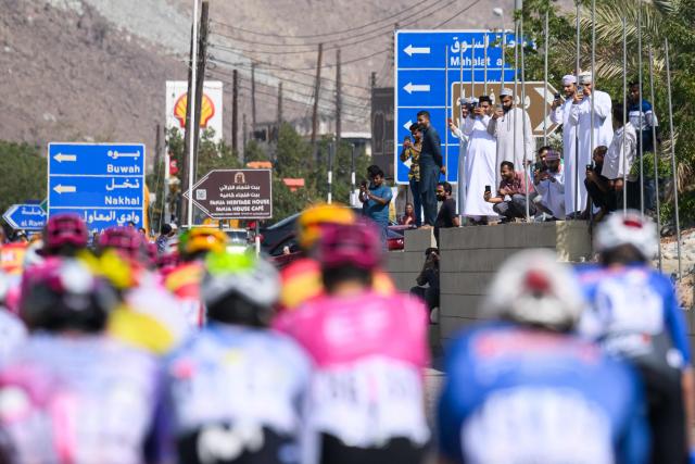 People watch the pack rides during the 2nd stage of the Tour of Oman cycling race from Al Rustaq Fort to Yitti Hills, on February 8, 2026. (Photo by Loic VENANCE / AFP)