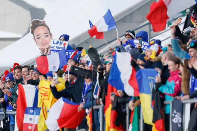 French supporters hold a cutout of the face of France's Lou Jeanmonnot as they celebrate France winning gold in the mixed biathlon 4 x 6km relay event during the Milano Cortina 2026 Winter Olympic Games at the Anterselva Biathlon Arena (Sudtirol Arena) in Anterselva (Val Pusteria) on February 8, 2026. (Photo by Odd ANDERSEN / AFP)