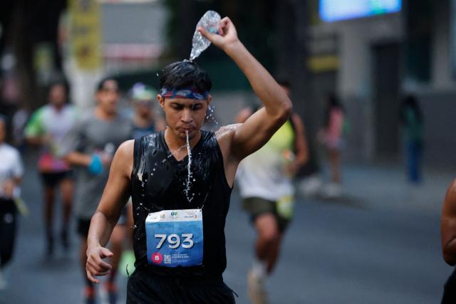A runner cools off with water as he takes part in the 10th edition of the CAF Marathon in Caracas on February 8, 2026. (Photo by Pedro MATTEY / AFP)