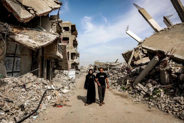 Etedal Rayyan (29), who recently returned back to Gaza from Egypt through the Rafah border crossing, walks with and her husband past the rubble of destroyed buildings in the Jabalia camp for Palestinian refugees in the northern Gaza Strip on February 8, 2026. Rayyan was shot twice in her right leg in January 2024, after which she was evacuated to Egypt for treatment with her family, and finally returned over a year later after the Rafah border crossing reopened. (Photo by Omar AL-QATTAA / AFP)