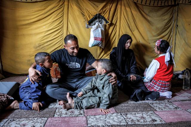 Etedal Rayyan (29), who recently returned back to Gaza from Egypt through the Rafah border crossing, sits with her husband and children in the Jabalia camp for Palestinian refugees in the northern Gaza Strip on February 8, 2026. Rayyan was shot twice in her right leg in January 2024, after which she was evacuated to Egypt for treatment with her family, and finally returned over a year later after the Rafah border crossing reopened. (Photo by Omar AL-QATTAA / AFP)