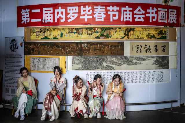 TOPSHOT - Young women wearing traditional costumes gather at a Chinese calligraphy workshop stall during celebrations marking the Chinese Lunar New Year in Nairobi, on February 8, 2026, ahead of the upcoming Lunar New Year of the Horse. (Photo by Luis TATO / AFP)