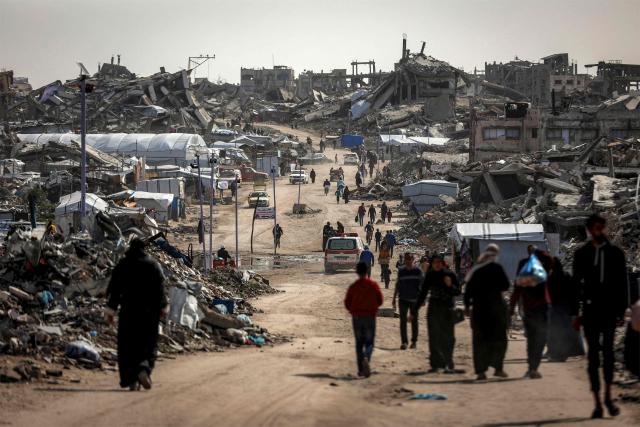 People walk past the rubble of destroyed buildings in the Jabalia camp for Palestinian refugees in the northern Gaza Strip on February 8, 2026. Since October 10, a fragile US-sponsored truce in Gaza has largely halted the fighting between Israeli forces and Hamas, but both sides have alleged frequent violations. (Photo by Omar AL-QATTAA / AFP)