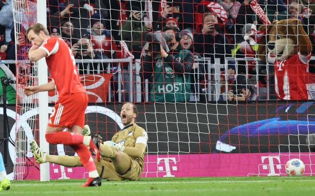Hoffenheim's German goalkeeper #01 Oliver Baumann (R) reacts after failing to save a penalty as Bayern Munich's English forward #09 Harry Kane celebrates during the German first division Bundesliga football match between FC Bayern Munich and TSG 1899 Hoffenheim in Munich, southern Germany on February 8, 2026. (Photo by Alexandra BEIER / AFP) / DFL REGULATIONS PROHIBIT ANY USE OF PHOTOGRAPHS AS IMAGE SEQUENCES AND/OR QUASI-VIDEO