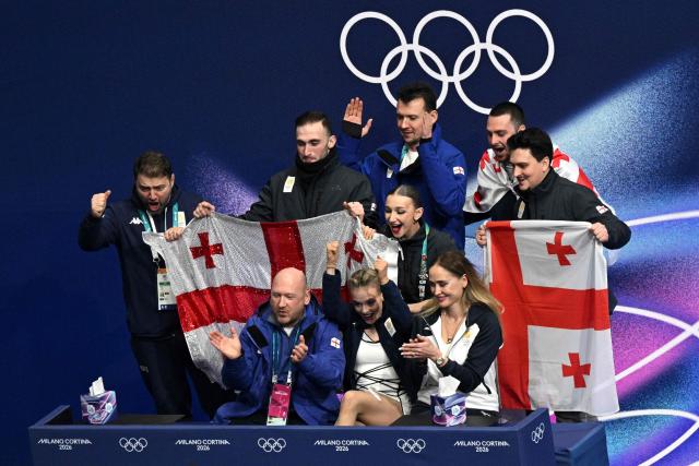 Georgia's Anastasiia Gubanova (C) reacts in the kiss and cry area after competing in the figure skating women's singles free skating team event during the Milano Cortina 2026 Winter Olympic Games at Milano Ice Skating Arena in Milan on February 8, 2026. (Photo by Antonin THUILLIER / AFP)