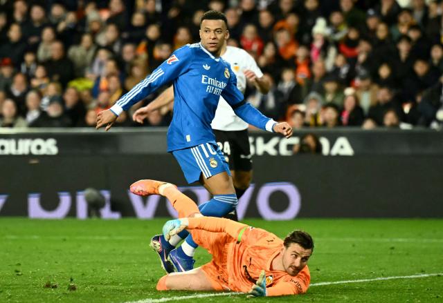 TOPSHOT - Real Madrid's French forward #10 Kylian Mbappe scores his team's second goal in spite of Valencia's North Macedonian goalkeeper # 01 Stole Dimitrievski (down) during the Spanish league football match between Valencia CF and Real Madrid CF at Mestalla Stadium in Valencia on February 8, 2026. (Photo by JOSE JORDAN / AFP)