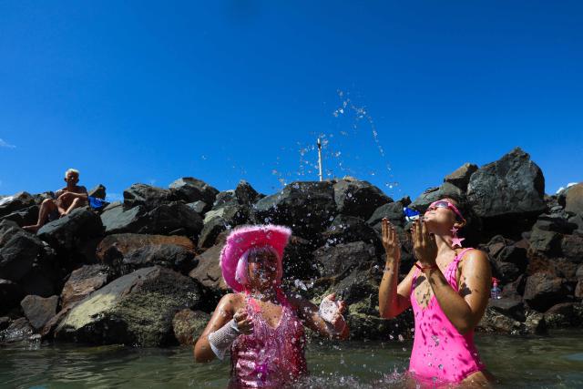 TOPSHOT - Revelers cool off in the sea during a carnival street group parade in the city of Salvador, Bahia state, Brazil, on February 8, 2026. The parade ends with a sea bath at Preguica Beach and pays tribute to the song “Ladeira da Preguiзa,” composed by Brazilian musician Gilberto Gil and performed by the late Brazilian singer Elis Regina. (Photo by ANTONELLO VENERI / AFP)