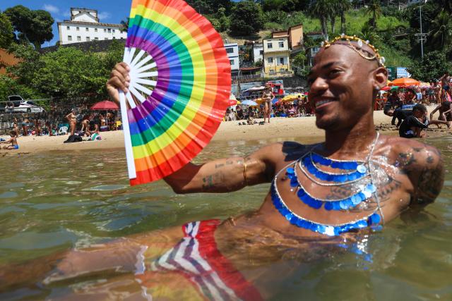 TOPSHOT - A reveler cools off in the sea during a carnival street group parade in the city of Salvador, Bahia state, Brazil, on February 8, 2026. The parade ends with a sea bath at Preguica Beach and pays tribute to the song “Ladeira da Preguiзa,” composed by Brazilian musician Gilberto Gil and performed by the late Brazilian singer Elis Regina. (Photo by ANTONELLO VENERI / AFP)