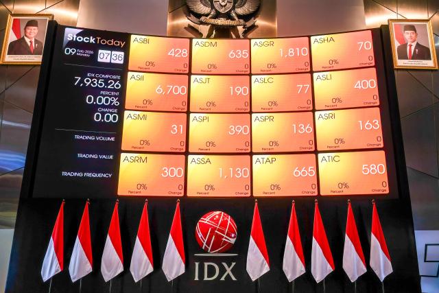 Portraits of Indonesia's President Prabowo Subianto (top L) and Vice President Gibran Rakabuming Raka (top L) flank a screen for stock market movements at the Indonesia Stock Exchange ahead of the day's trading in Jakarta on February 9, 2026. (Photo by BAY ISMOYO / AFP)