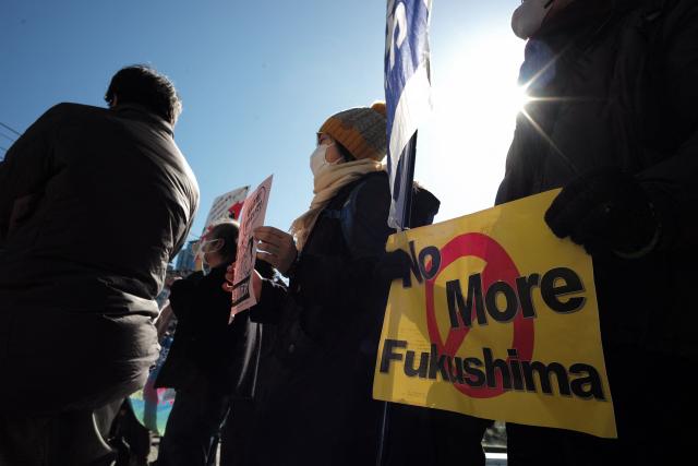A participant taking part in a demonstration against the restart of the Kashiwazaki-Kariwa Nuclear Power Plant holds up a sign reading "No More Fukushima" in front of Tokyo Electric Power Company's headquarters in Tokyo on February 9, 2026. Japan switched on the world's biggest nuclear power plant again February 9, its operator said, after an earlier attempt was quickly suspended due to a minor glitch. (Photo by Kazuhiro NOGI / AFP)
