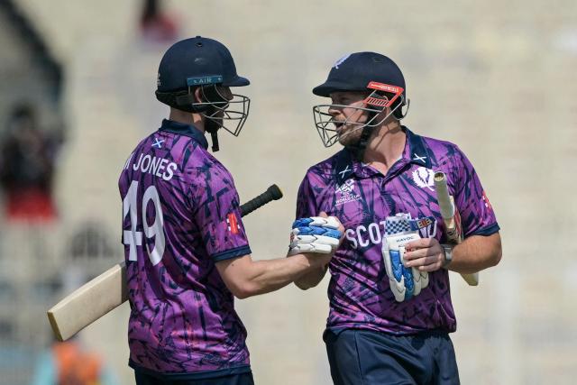 Scotland's George Munsey (R) is congratulated by Michael Jones for his innings as he walks back to the pavilion after his dismissal during the 2026 ICC Men's T20 Cricket World Cup group stage match between Scotland and Italy at the Eden Gardens in Kolkata on February 9, 2026. (Photo by Dibyangshu SARKAR / AFP)