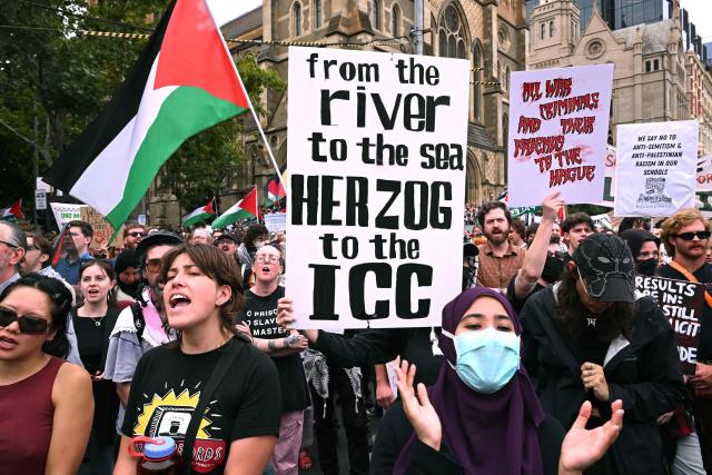 People hold up placards during a protest rally against a four-day state visit by Israeli President Isaac Herzog, in Melbourne on February 9, 2026. (Photo by William WEST / AFP)