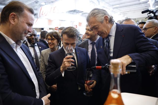 France's President Emmanuel Macron smells wine next to French winemaker Gerard Bertrand (R) as he visits the Wine Paris 2026 fair at the Porte de Versailles exhibition centre in Paris on February 9, 2026. (Photo by Yoan VALAT / POOL / AFP)