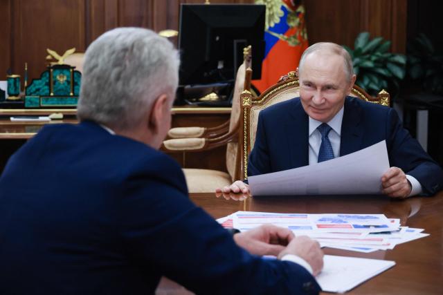 In this pool photograph distributed by the Russian state agency Sputnik, Russia's President Vladimir Putin meets with Moscow Mayor Sergei Sobyanin in Moscow on February 9, 2026. (Photo by Vyacheslav PROKOFYEV / POOL / AFP)