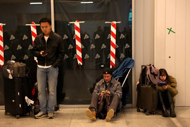 Commuters wait at Madrid's Chamartin train station, on February 9, 2026, amid a national strike by Spanish train drivers' union to demand railway safety measures following deadly accidents, in Adamuz and in Gelida. The sign reads 'If there were no more trains?'. Spanish train drivers began a three-day strike, demanding greater safety for their profession after two accidents claimed 47 lives last month, leaving thousands of passengers stranded. (Photo by Pierre-Philippe MARCOU / AFP)