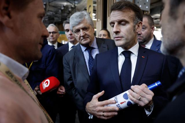 French President Emmanuel Macron (C-R) holds a bottle of wine next to French junior Minister in charge of external trade Nicolas Forissier as he visits the Wine Paris 2026 fair at the Porte de Versailles exhibition centre in Paris on February 9, 2026. (Photo by Yoan VALAT / POOL / AFP)