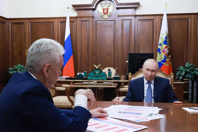 In this pool photograph distributed by the Russian state agency Sputnik, Russia's President Vladimir Putin meets with Moscow Mayor Sergei Sobyanin in Moscow on February 9, 2026. (Photo by Vyacheslav PROKOFYEV / POOL / AFP)