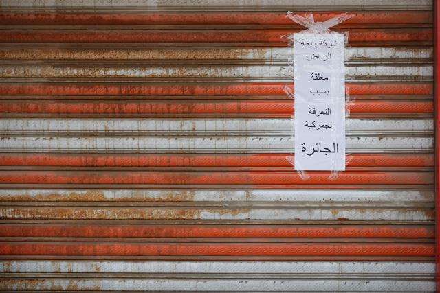 A photograph shows a sign on a closed retail store selling electrical materials, stating that the shop is closed due to an increase in customs tariffs, during a strike by shop owners in Baghdad on February 9, 2026. (Photo by AHMAD AL-RUBAYE / AFP)