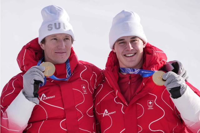 Gold medallists Switzerland's Tanguy Nef (L) and Switzerland's Franjo von Allmen celebrate  on the podium of the men's team combined alpine skiing event during the Milano Cortina 2026 Winter Olympic Games at the Stelvio Ski Centre in Bormio (Valtellina) on February 9, 2026. (Photo by Dimitar DILKOFF / AFP)