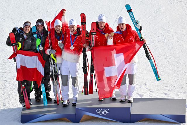 From (L-R) Austria's silver medalists Manuel Feller and Vincent Kriechmayron stand with joint silver medalists Switzerland's Loic Meillard and Marco Odermatt along with Switzerland's gold medalists Tanguy Nef and Franjo von Allmen on the podium of the men's team combined alpine skiing event during the Milano Cortina 2026 Winter Olympic Games at the Stelvio Ski Centre in Bormio (Valtellina) on February 9, 2026. (From L) Austria's Manuel Feller, Austria's Vincent Kriechmayr, Guest, FIS Louise SEPPEY, Norway's Ingrid Landmark Tandrevold, Switzerland's Tanguy Nef and Switzerland's Franjo von Allmen (Photo by Fabrice COFFRINI / AFP)