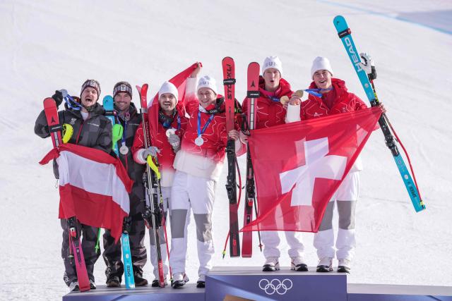 Tied Silver medallists Switzerland's Loic Meillard and Switzerland's Marco Odermatt (C) and Austria's Manuel Feller and Austria's Vincent Kriechmayr (L) and Gold medallists Switzerland's Tanguy Nef and von Switzerland's Franjo von Allmen (R) pose on the podium of the men's team combined alpine skiing event during the Milano Cortina 2026 Winter Olympic Games at the Stelvio Ski Centre in Bormio (Valtellina) on February 9, 2026. (Photo by Dimitar DILKOFF / AFP)