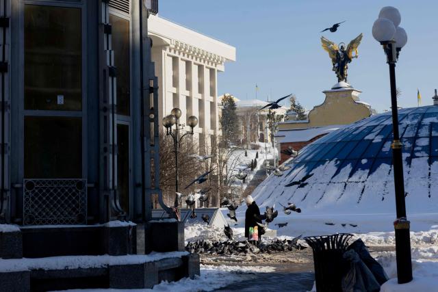 A pedestrian walks past a flock of pigeons in the centre of Kyiv on February 9, 2026, amid the Russian invasion of Ukraine. (Photo by Tetiana DZHAFAROVA / AFP)