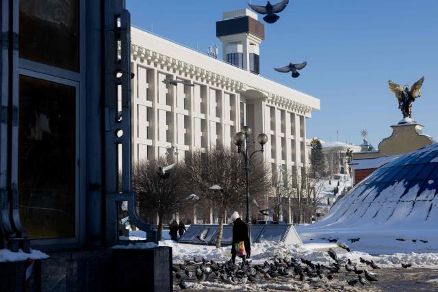 A pedestrian walks past a flock of pigeons in the centre of Kyiv on February 9, 2026, amid the Russian invasion of Ukraine. (Photo by Tetiana DZHAFAROVA / AFP)