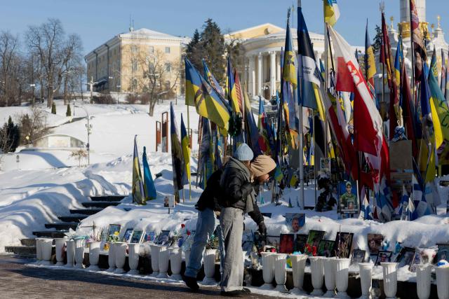 Pedestrians pay their respects before the Memorial for the Fallen Ukrainian and Foreign Fighters on Independence Square in Kyiv on February 9, 2026, amid the Russian invasion of Ukraine. (Photo by Tetiana DZHAFAROVA / AFP)