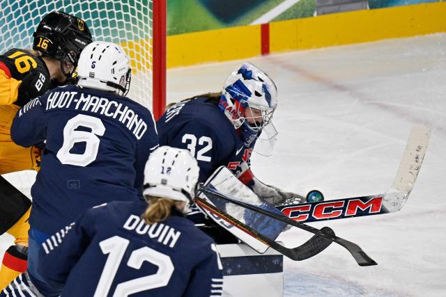 France's #32 Alice Philbert (R) saves the puck during the women's preliminary round Group B Ice Hockey match between Germany and France at the Milano Rho Ice Hockey Arena at the Milano Cortina 2026 Winter Olympic Games in Milan, on February 9, 2026. (Photo by Alexander NEMENOV / AFP)