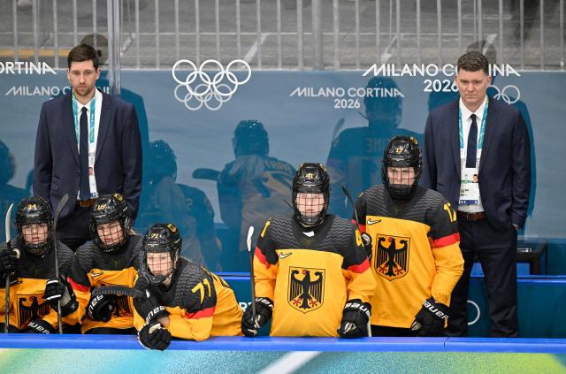 Germany's Canadian head coach Jeff MacLeod (R) and players look on during the women's preliminary round Group B Ice Hockey match between Germany and France at the Milano Rho Ice Hockey Arena at the Milano Cortina 2026 Winter Olympic Games in Milan, on February 9, 2026. (Photo by Alexander NEMENOV / AFP)