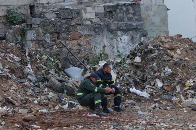 Lebanese rescuers take a break during a search for survivors on February 9, 2026, in the rubble of an old residential building that collapsed in the Bab al-Tabbaneh neighborhood of Tripoli a day earlier. The death toll in a building collapse in the northern Lebanese city of Tripoli rose to 14 after search and rescue operations ended, the civil defence chief said on February 9. (Photo by Anwar AMRO / AFP)