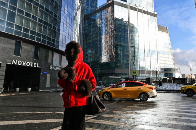A woman crosses a street at the Moscow International Business Centre (Moskva City) in Moscow on February 9, 2026. (Photo by HECTOR RETAMAL / AFP)