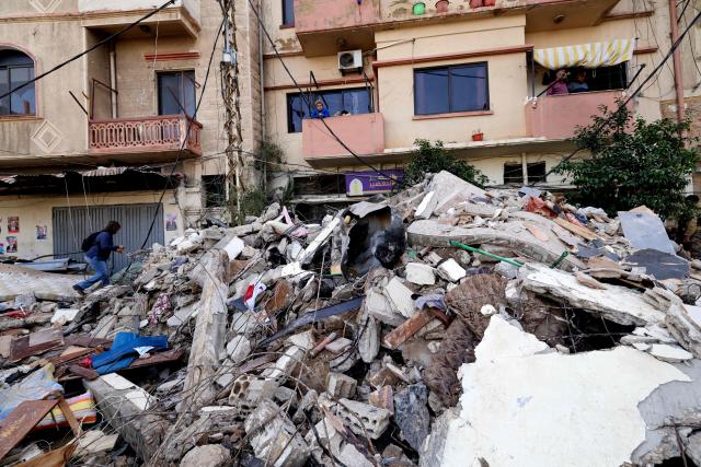Lebanese residents look on February 9, 2026, at the rubble of an old residential building that collapsed in the Bab al-Tabbaneh neighborhood of Tripoli a day earlier. The death toll in a building collapse in the northern Lebanese city of Tripoli rose to 14 after search and rescue operations ended, the civil defence chief said on February 9. (Photo by Anwar AMRO / AFP)