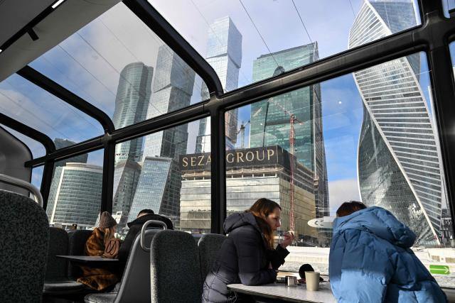 People travel on a ferry on the Moskva river with buildings of the Moscow International Business Centre (Moskva City) seen in distance, in Moscow on February 9, 2026. (Photo by Hector RETAMAL / AFP)