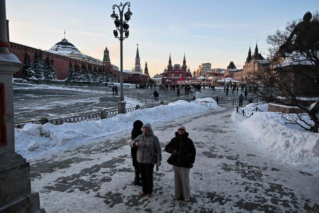Women cross themselves in front of St. Basil's cathedral in central Moscow on February 9, 2026. (Photo by Hector RETAMAL / AFP)