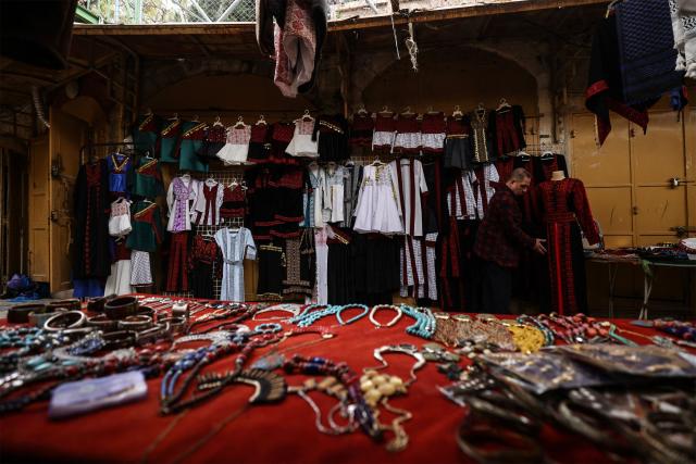 A Palestinian man adjusts a dress at a shop selling traditional outfits in Hebron's Old City, in the Israeli-occupied West Bank, on February 9, 2026. Israel's security cabinet approved a series of measures on February 8, set to deepen Israeli control over the occupied West Bank, paving the way for further settlement expansion in the Palestinian territory. (Photo by HAZEM BADER / AFP)
