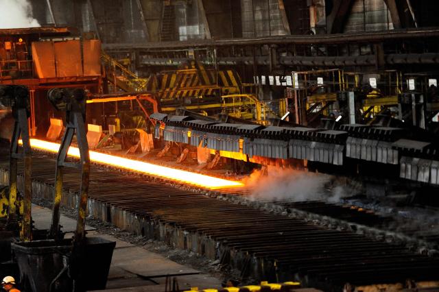 (FILES) This photo taken on March 21, 2013 shows hot steel coming out of a hot wide strip mill at the Arcelor Mittal steel plant in Grande-Synthe, northern France. France's leading steel producer is expected to announce the decarbonization project for one of its plants, which will include the launch of its first electric arc furnace, during the visit of French President Emmanuel Macron on Februar 10, 2026. (Photo by PHILIPPE HUGUEN / AFP)