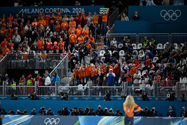 Fans cheer as Netherlands' Jutta Leerdam (bottom R) stands after winning gold in the speed skating women's 1000m during the Milano Cortina 2026 Winter Olympic Games at Milano Speed Skating Stadium in Milan on February 9, 2026. (Photo by WANG Zhao / AFP)
