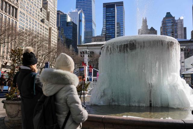People take pictures of a frozen fountain in Bryant Park amid freezing temperatures in New York City on February 9, 2026. (Photo by ANGELA WEISS / AFP)