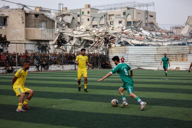 Palestinians watch a five-a-side football match amid the rubble of destroyed buildings in Gaza City on February 9, 2026. Despite a US-brokered truce that entered its second phase last month, violence has continued in the Palestinian territory, with Israel and Hamas trading accusations. (Photo by Omar AL-QATTAA / AFP)