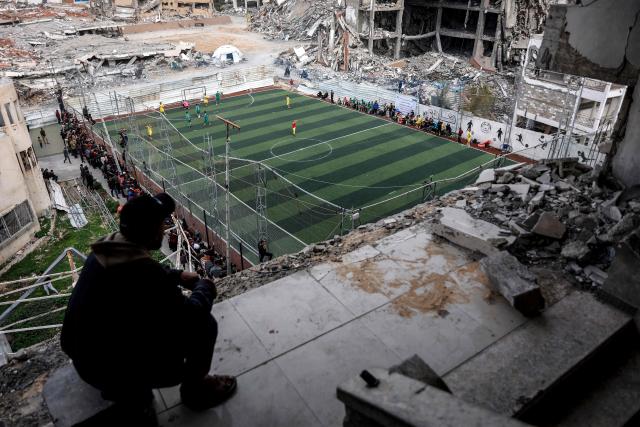 TOPSHOT - Palestinians watch a five-a-side football match amid the rubble of destroyed buildings in Gaza City on February 9, 2026. Despite a US-brokered truce that entered its second phase last month, violence has continued in the Palestinian territory, with Israel and Hamas trading accusations. (Photo by Omar AL-QATTAA / AFP)