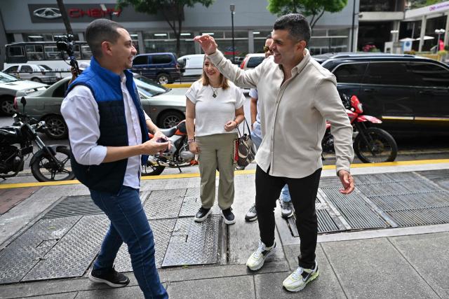 Venezuelan former political prisoners, journalists Gabriel Gonzalez (L) and Julio Balza (R) of the Vente Venezuela political party, led by Nobel Peace Prize laureate Maria Corina Machado, greet outside the United Nations Development Programme(PNUD)building in Caracas on February 9, 2026. Machado denounced the “kidnapping” of leader Juan Pablo Guanipa, who was released from prison on Sunday as part of a process to free political prisoners announced days after the overthrow of Nicolas Maduro. (Photo by Juan BARRETO / AFP)