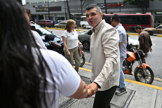 Venezuelan former political prisoner, journalist Julio Balza (R) of the Vente Venezuela political party, led by Nobel Peace Prize laureate Maria Corina Machado, is greeted by a woman outside the United Nations Development Programme(PNUD)building in Caracas on February 9, 2026. Machado denounced the “kidnapping” of leader Juan Pablo Guanipa, who was released from prison on Sunday as part of a process to free political prisoners announced days after the overthrow of Nicolas Maduro. (Photo by Juan BARRETO / AFP)