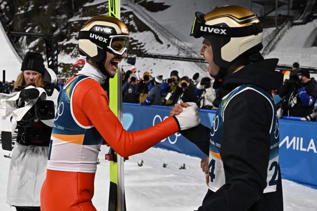 Bronze medallist Switzerland's Gregor Deschwanden (L) celebrates with Switzerland's Sandro Hauswirth after jumping during the men's ski jumping normal hill individual final round of the Milano Cortina 2026 Winter Olympic Games at Predazzo Ski Jumping Stadium in Predazzo (Val di Fiemme), on February 9, 2026. (Photo by Javier SORIANO / AFP)