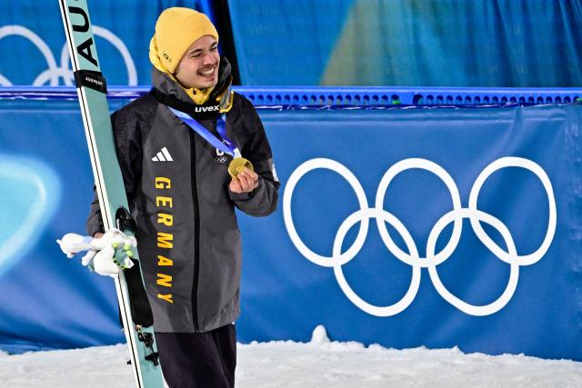Gold medallist Germany's Philipp Raimund holds his medal as he celebrates on the podium after winning the men's ski jumping normal hill individual final round of the Milano Cortina 2026 Winter Olympic Games at Predazzo Ski Jumping Stadium in Predazzo (Val di Fiemme), on February 9, 2026. (Photo by Tobias SCHWARZ / AFP)