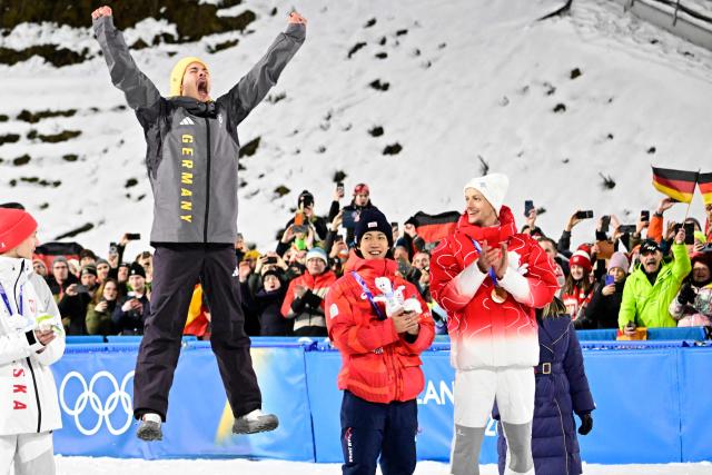 (From L) Silver medallist Poland's Kacper Tomasiak, gold medallist Germany's Philipp Raimund and Bronze medallists who tied for third place Japan's Ren Nikaido and Switzerland's Gregor Deschwanden celebrate on the podium for the men's ski jumping normal hill individual final round of the Milano Cortina 2026 Winter Olympic Games at Predazzo Ski Jumping Stadium in Predazzo (Val di Fiemme), on February 9, 2026. (Photo by Tobias SCHWARZ / AFP)