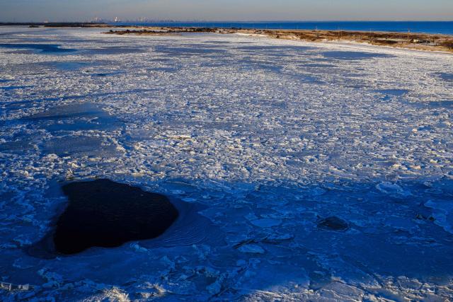 The Sandy Hook Bay is seen frozen as the Manhattan skyline looms in the distance in Highlands, New Jersey on February 9, 2026. (Photo by CHARLY TRIBALLEAU / AFP)